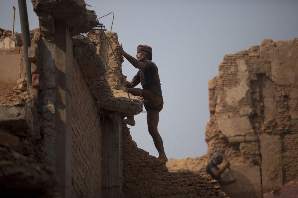 An Indian labourer climbs the wall of a building undergoing demolition in in Uttar Pradesh state.