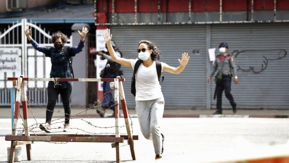 People react as riot police fire tear gas during a protest against the military coup in Yangon, Myanmar