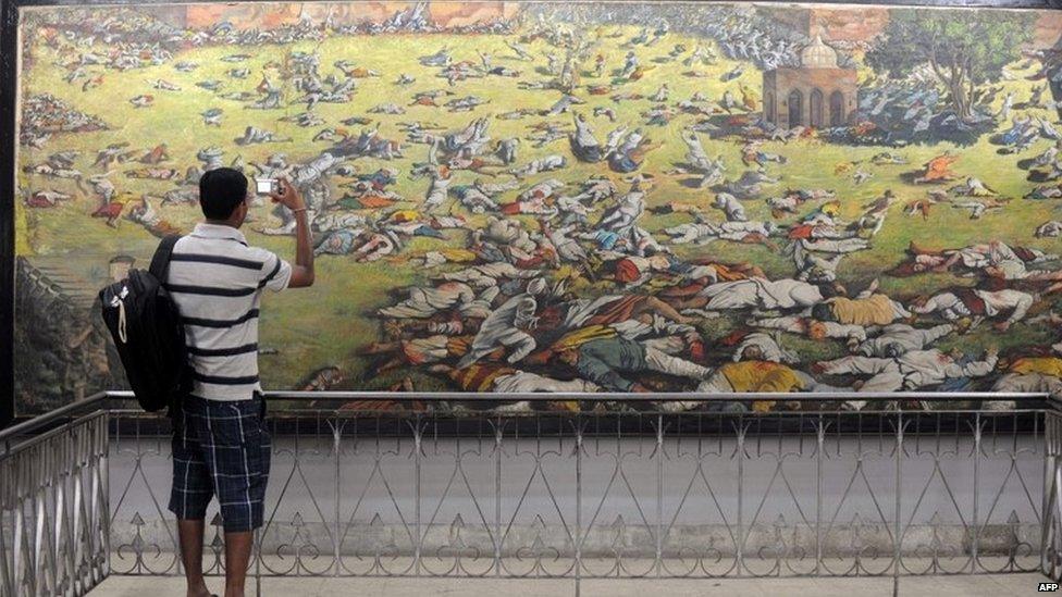 An Indian man takes a photograph of a painting depicting the Jallianwala Bagh massacre in Amritsar on April 12, 2011