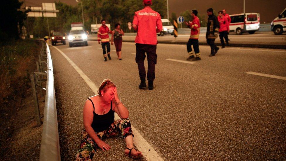 A woman sits on a street during a forest fire in Pedrógão Grande, Leiria District, Center of Portugal, 17 June 2017