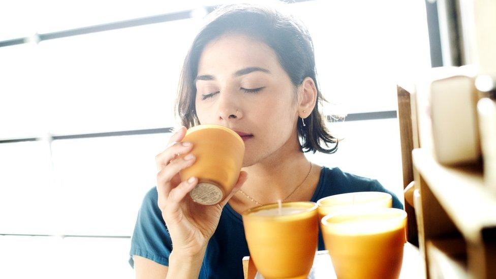 Stock shot of woman sniffing candles