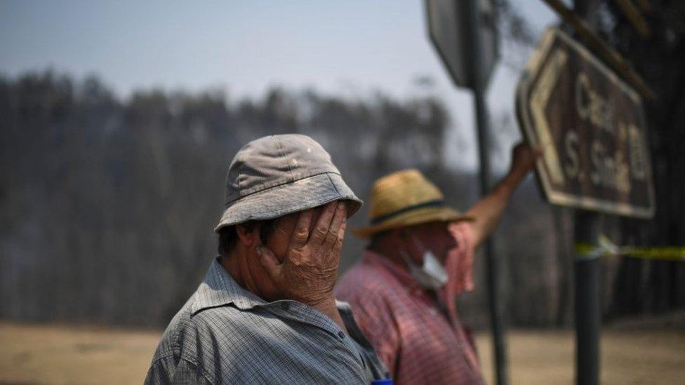 A couple stand on the roadside watching firefighters passing by in Figueiro dos Vinhos on 18 June, 2017.