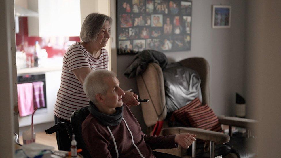 A woman points a remote control while a man watches