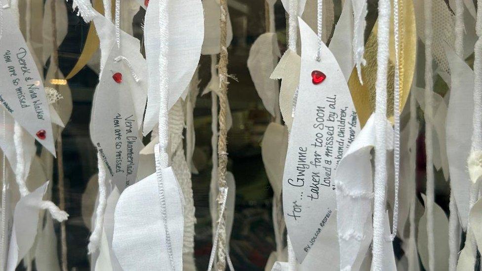 Card leaves with messages written on them hanging in a window