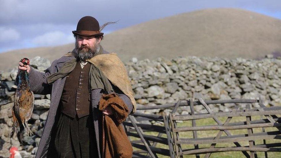 A man dressed an 1800s-style poacher holding a dead pheasant