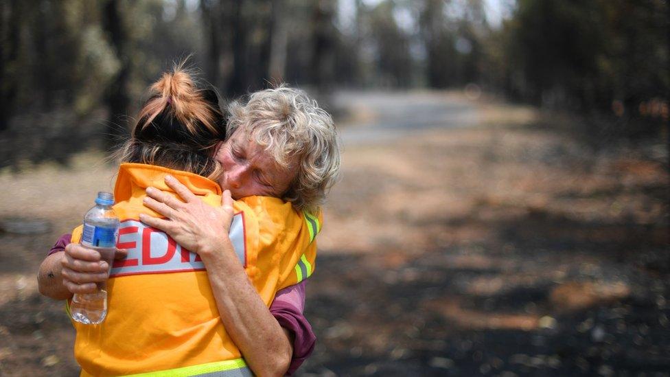 A fruit farmer is comforted by a journalist in Batlow, New South Wales