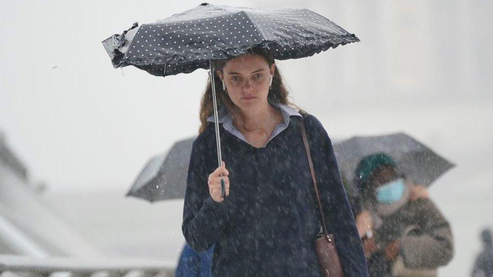 A woman seen during heavy rain in central London on 2 August