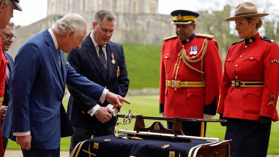 King Charles III is presented with a sword as he formally accepts the role of Commissioner-in-Chief of the Royal Canadian Mounted Police (RCMP) during a ceremony in the quadrangle at Windsor Castle