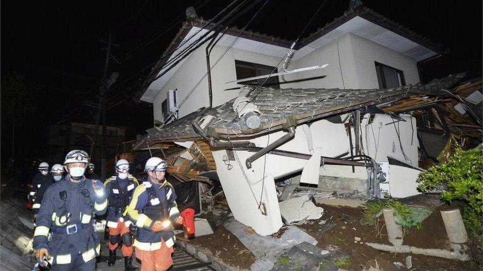 Firefighters check the damage of the collapsed house in Mashiki, near Kumamoto city, southern Japan, after the earthquake early Friday, April 15, 2016.