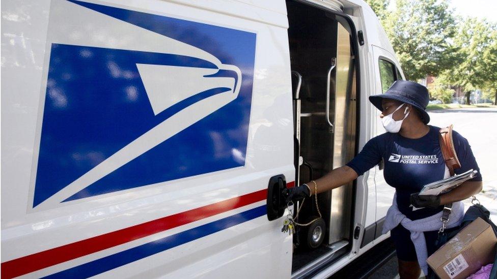 A mail carrier of the United States Postal Service delivers mail in Washington, DC, 18 August