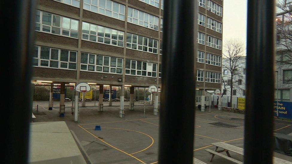 Image of a concreted yard at the school which is overlooked by basketball hoops and picnic tables