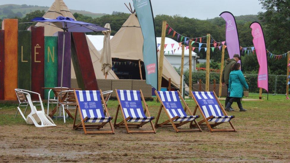 Cadeiriau haul gwag yn y mwd // Empty deckchairs in the mud