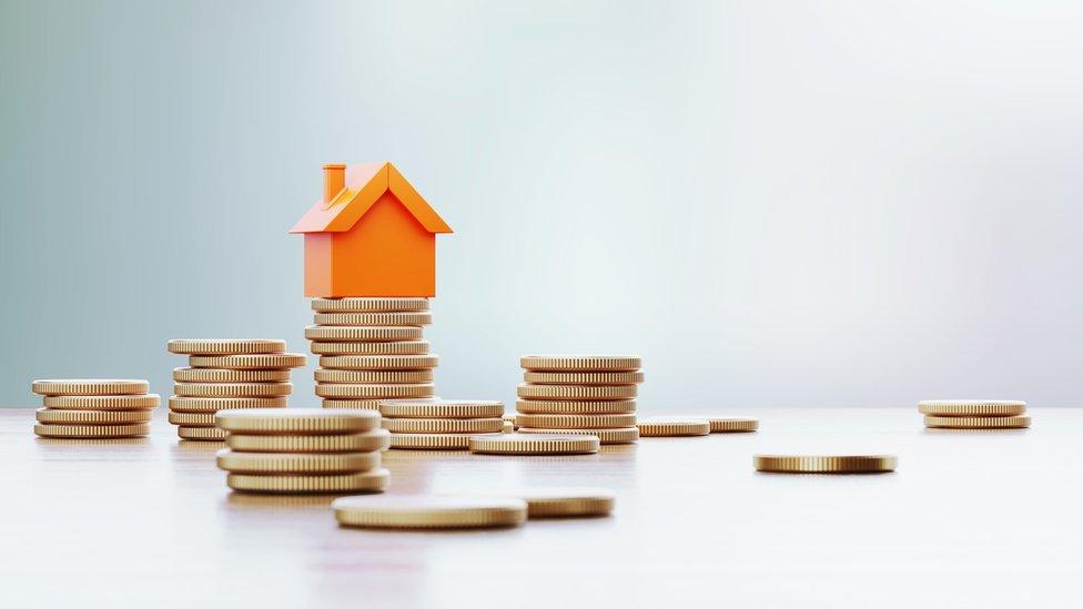 house figurine on top of coins