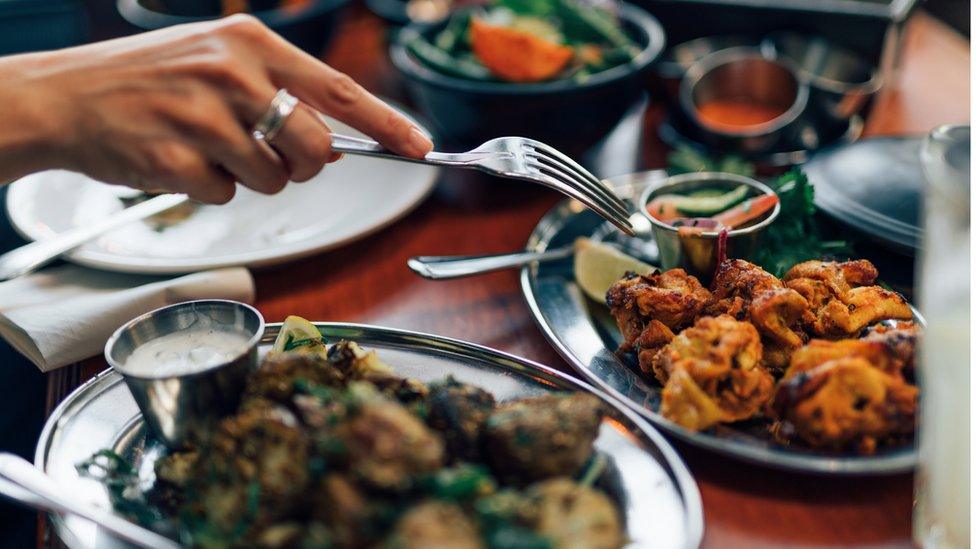 Indian grilled chicken (Chicken Tikka), roast spiced potatoes, yoghurt raita, nan bread and a bowl of vegetables.