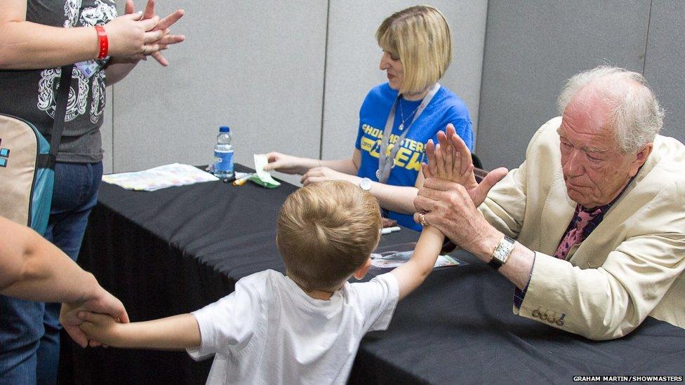 Michael Gambon high-fives a child