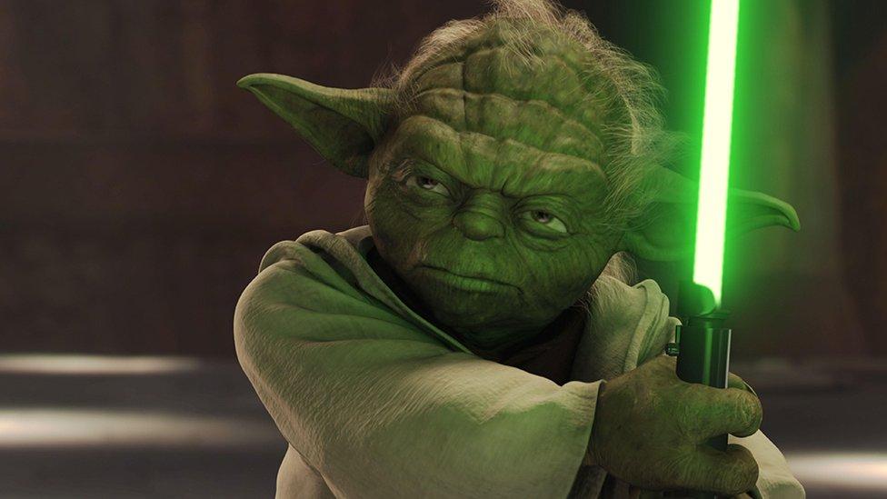 Yoda wielding a lighsaber