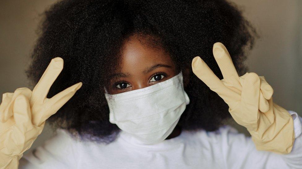 A South African wearing a face mask and gloves showing the victory signs