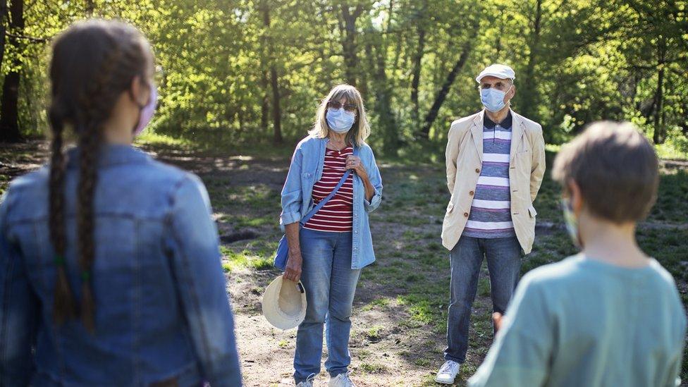 Adults wearing masks meeting children outdoors