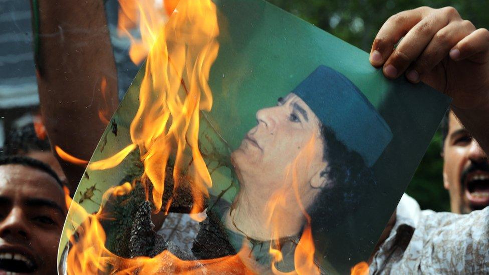 Libyan protesters burn an image of the country's leader Muammar Gaddafi in 2011