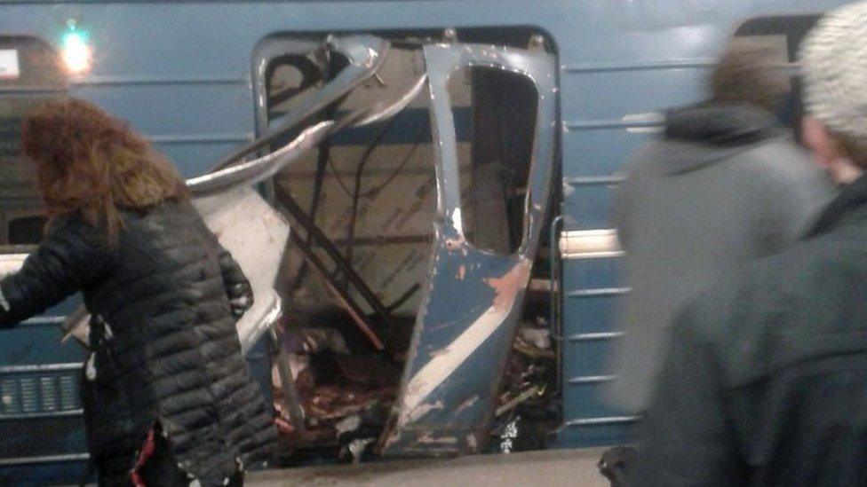 People in front of a damaged train door shortly after an explosion in a metro of Saint Petersburg, Russia