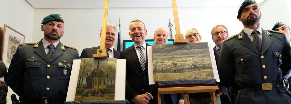 Axel Ruger (C), Director of the Van Gogh museum poses next to Congregation Leaving the Reformed Church in Nuenen" (L) and "The Beach At Scheveningen During A Storm" (R)