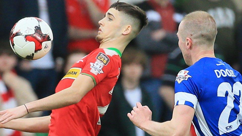 Jay Donnelly of Cliftonville in possession as Coleraine's Stephen Dooley moves in to challenge