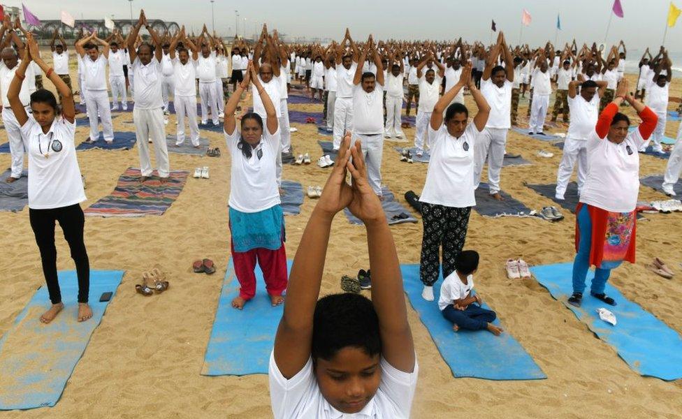 Indian children along with yoga enthusiasts take part in a yoga session to mark International Yoga Day on a beach in Chennai on June 21, 2019. - Indian Prime Minister Narendra Modi led the way for International Yoga Day on June 21, performing sun salutations and other flexible feats in a mass session with an estimated 30,000 other devotees of the discipline.