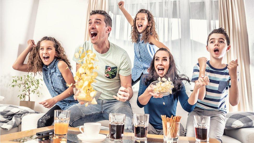 Family watch sports together with snacks