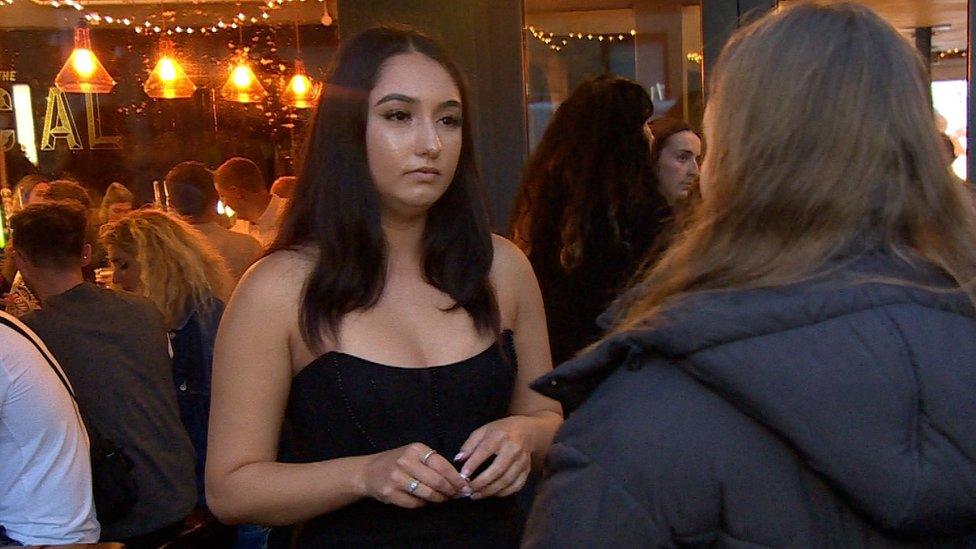 Woman in a black dress standing outside a bar