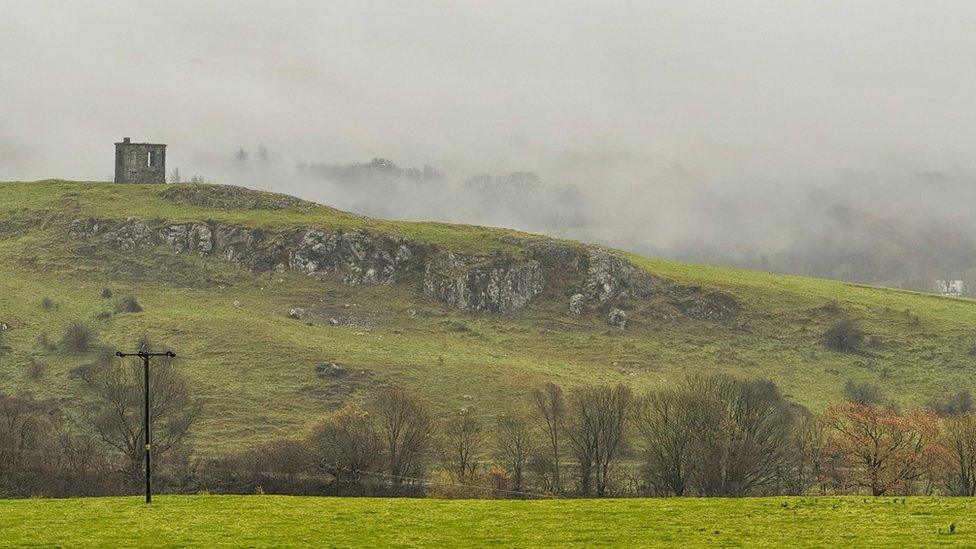 Low cloud shrouds a ruin on a hill