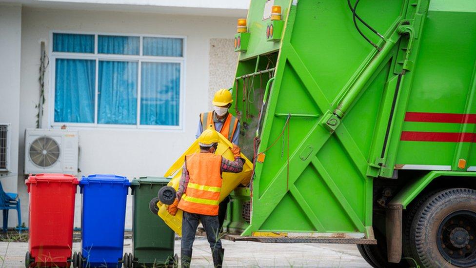 bin collectors putting rubbish into bin lorry