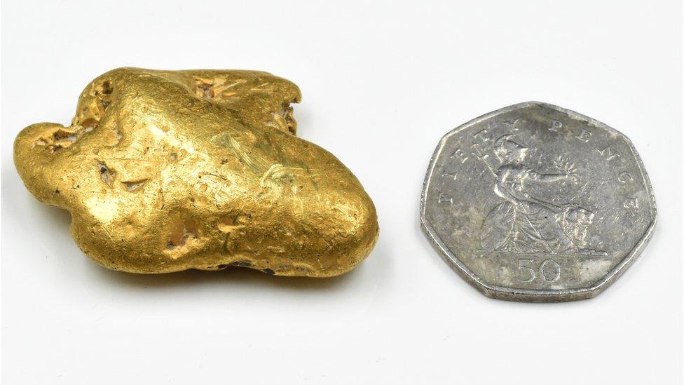 Gold nugget next to a 50 pence piece.