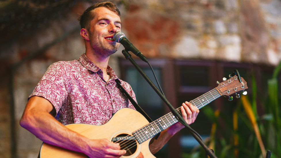 Sam Evans performing with a guitar