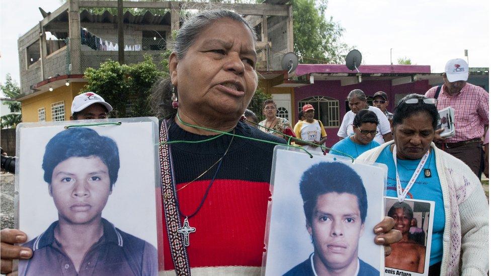 Clementina Murcia González holds up the pictures of her two sons