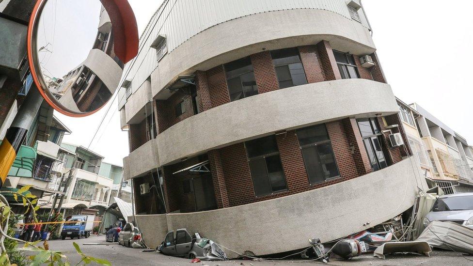 Crushed vehicles are seen under a building that was damaged after a powerful earthquake hit Tainan