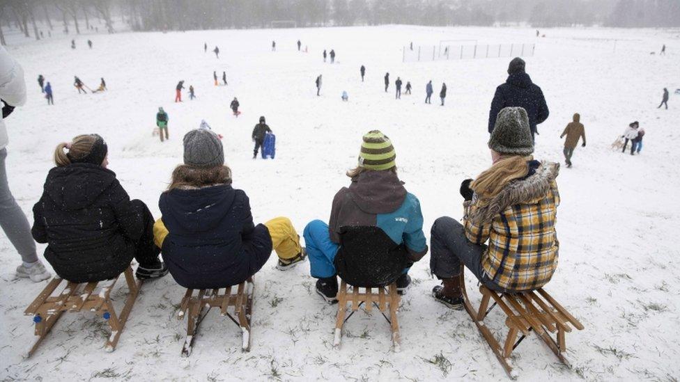 People enjoy a sled ride in the snow on a hill in Rotterdam