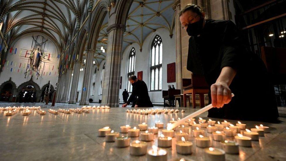 A verger lights one of 4,161 candles representing each death from Covid-19 in Lancashire county at Blackburn Cathedral