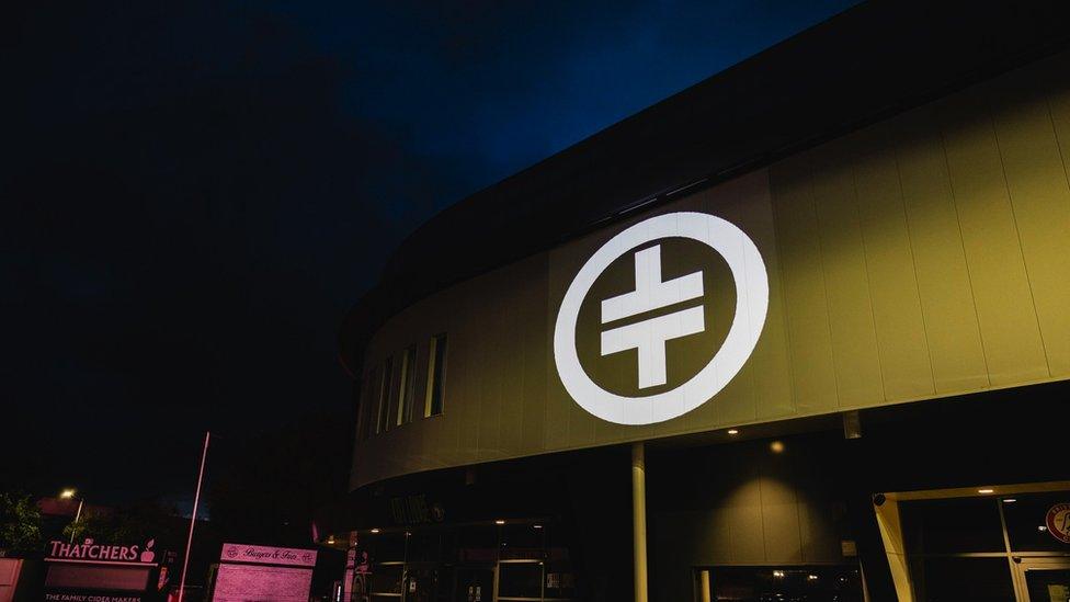 Ashton Gate Stadium with the Take That logo projected onto the outside of the building