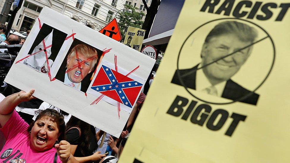 Anti-Trump protesters hold signs in Washington, DC.