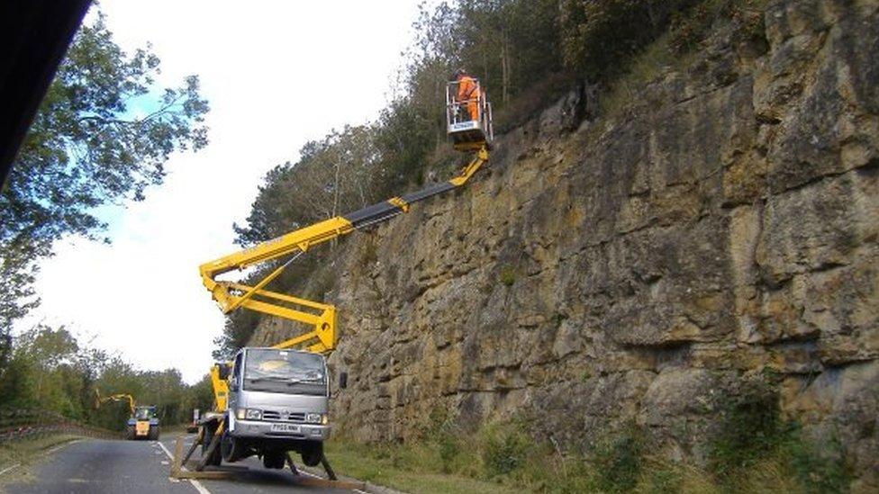 Man on a crane by a rockface