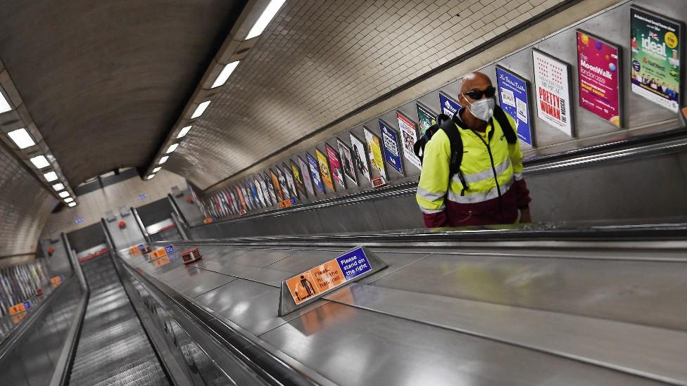 A commuter in a face mask on the London Underground escalators