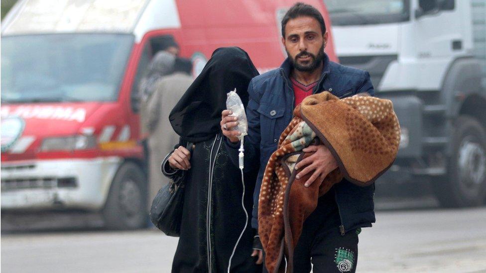 A man carries a child with an IV drip as he flees deeper into the remaining rebel-held areas of Aleppo, Syria December 12, 2016