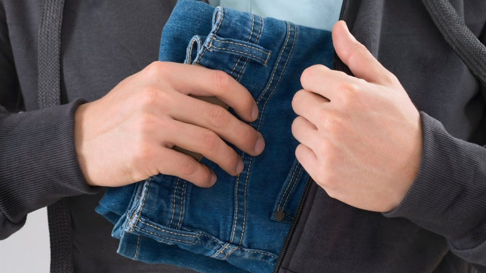 Person shoplifting a pair of jeans