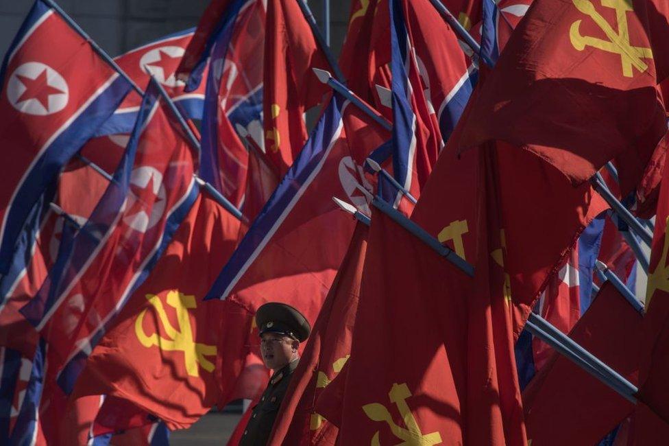 A Korean People's Army (KPA) soldier stands between flags prior to an opening ceremony for the Ryomyong Street housing development in Pyongyang on 13 April 2017.