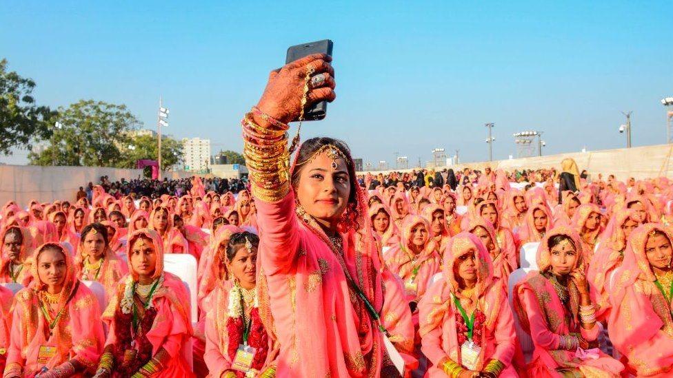 A bride takes a selfie with her wedding guests