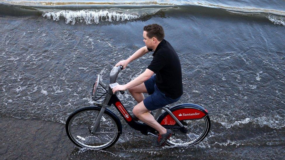 Man riding bike in Putney during high tide