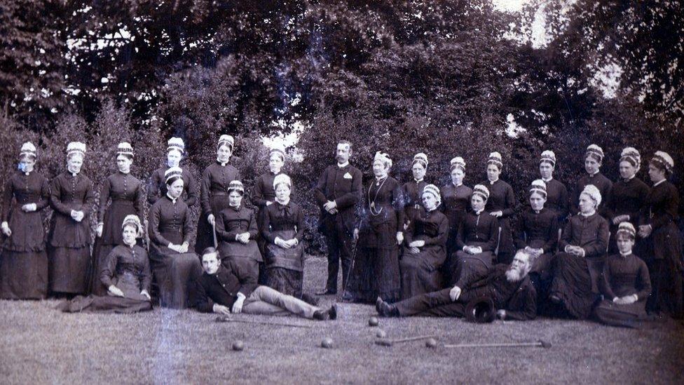 Officers and female staff in 1884 with Dr Llewellyn Cox and Matron Pugh centre, with croquet mallets and balls on the lawn