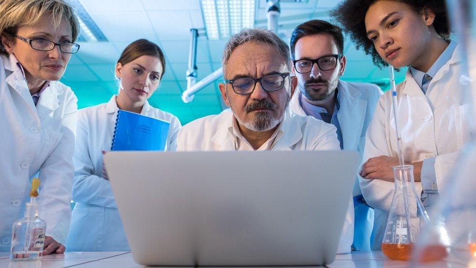 Team of scientists look at a laptop