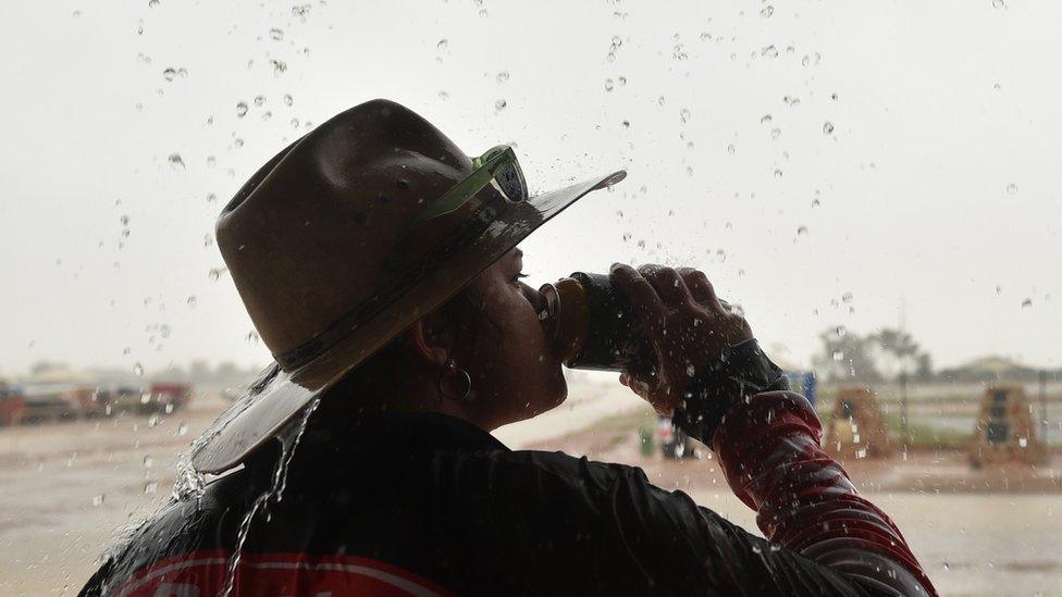 An Australian woman drinking beer in the rain