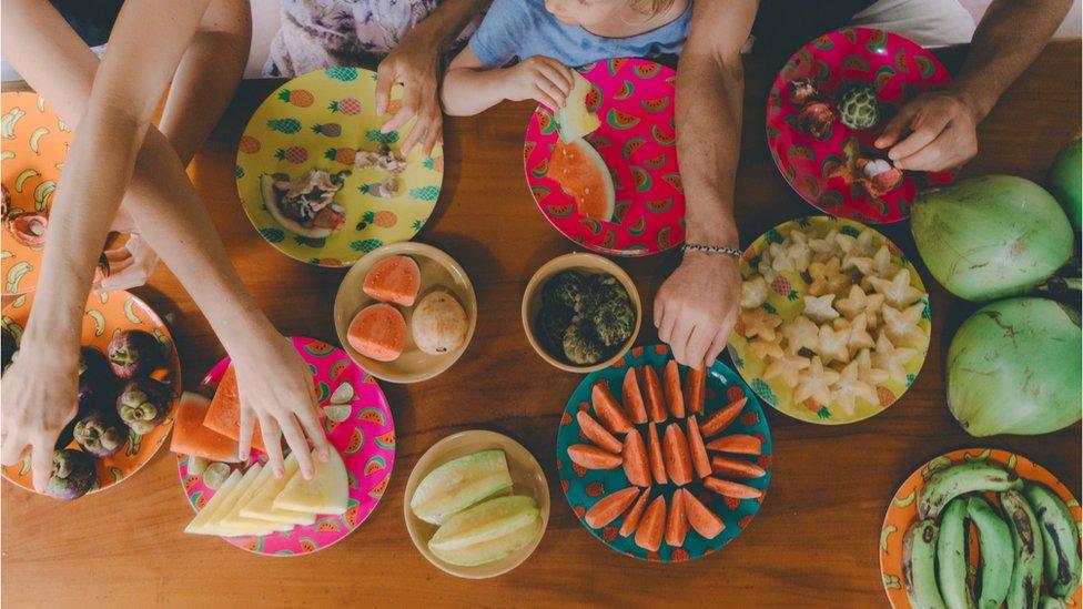 People reach for fruit placed on table